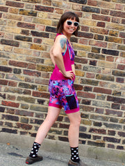 Rouleur Leggings View B - image of woman in brightly coloured bib shorts turning around with hands on hips in front of a brick wall