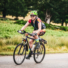 Rouleur Leggings View B - woman on a bicycle wearing ranbow shorts, jersey, and helmet against a grass background